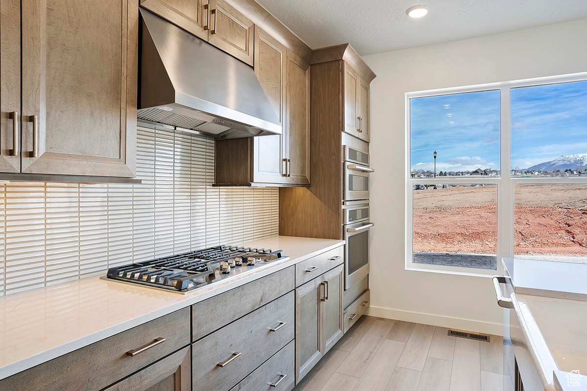 Gourmet kitchen features gorgeous maple cabinets, 36-inch gas cooktop with stainless steel hood, quartz countertops, farmhouse sink, built-in wall oven, walk-in pantry, and an island nearly 8 feet long.
