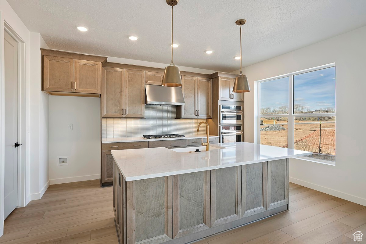 Gourmet kitchen features gorgeous maple cabinets, 36-inch gas cooktop with stainless steel hood, quartz countertops, farmhouse sink, built-in wall oven, walk-in pantry, and an island nearly 8 feet long.