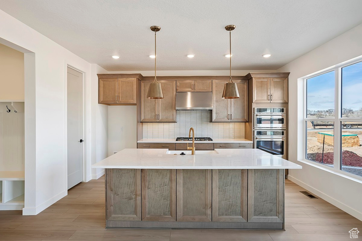 Gourmet kitchen features gorgeous maple cabinets, 36-inch gas cooktop with stainless steel hood, quartz countertops, farmhouse sink, built-in wall oven, walk-in pantry, and an island nearly 8 feet long.