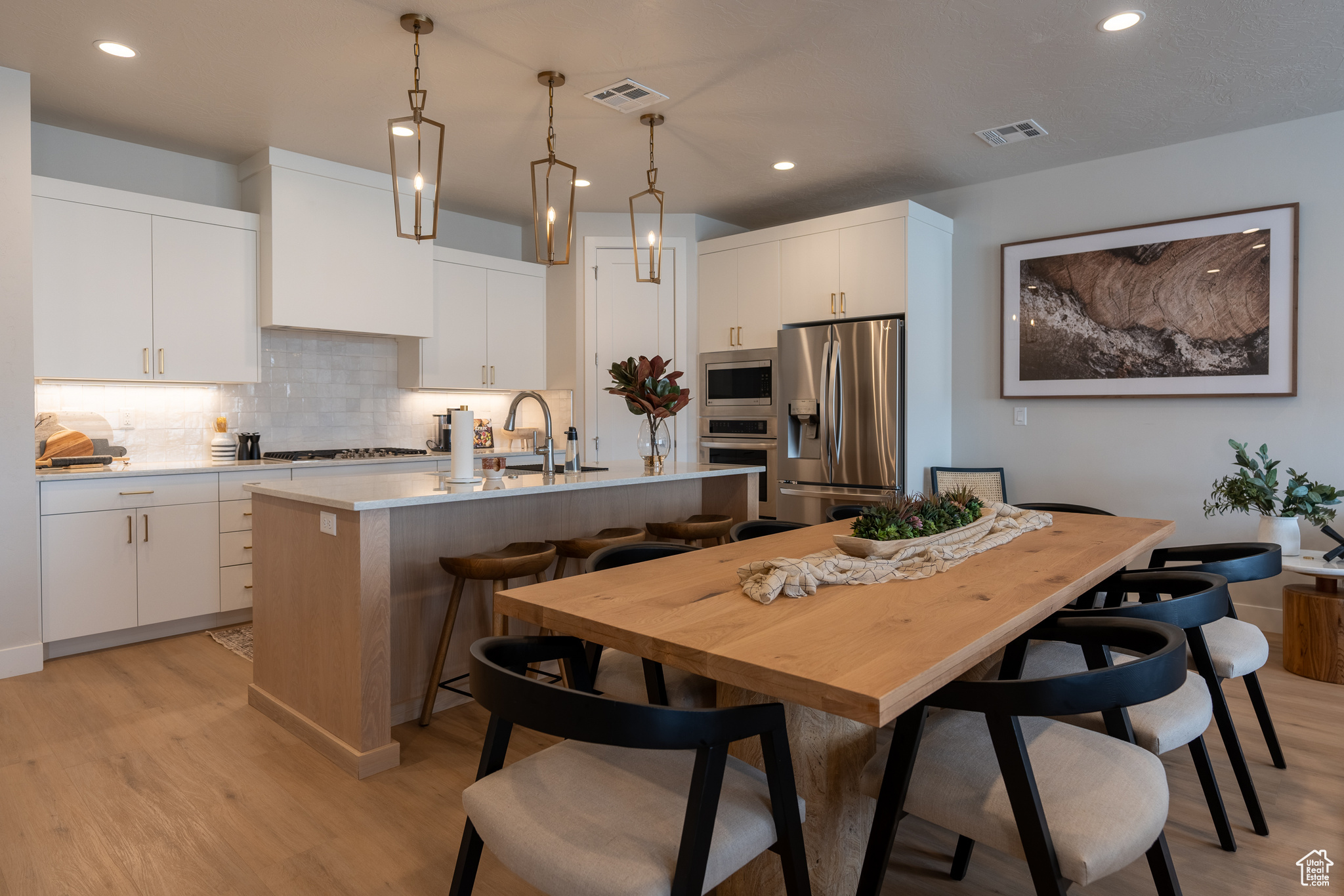 Kitchen with white cabinets, a kitchen island with sink, and stainless steel appliances