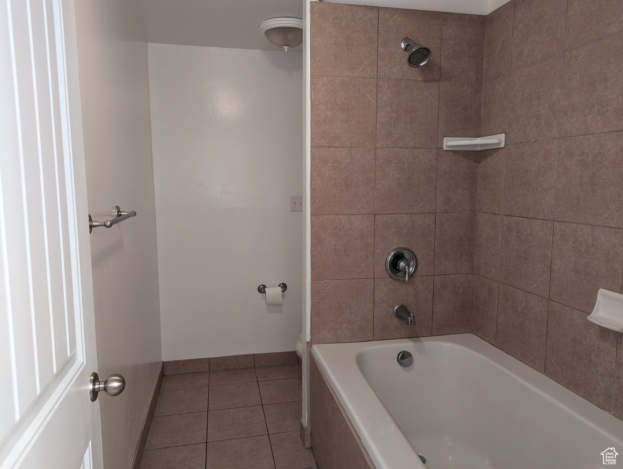 Bathroom featuring tiled shower / bath combo and tile patterned flooring