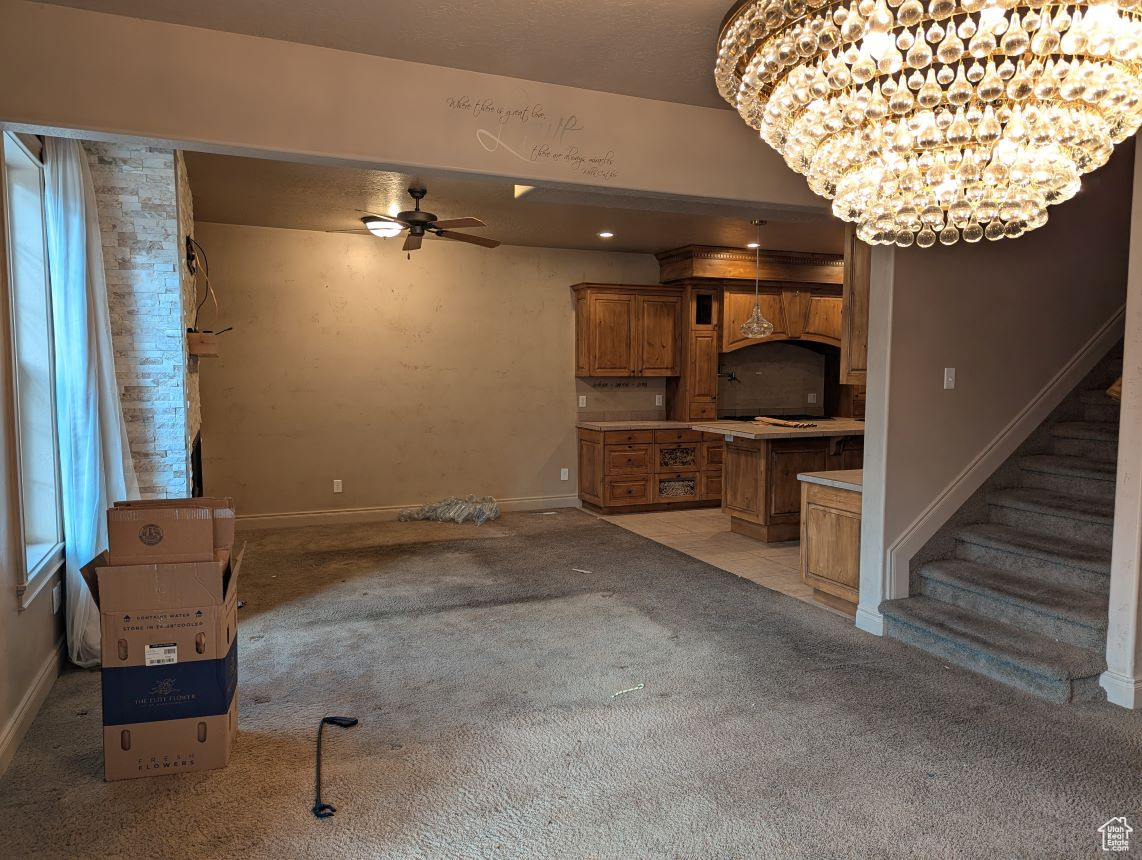 Carpeted living room featuring ceiling fan with notable chandelier
