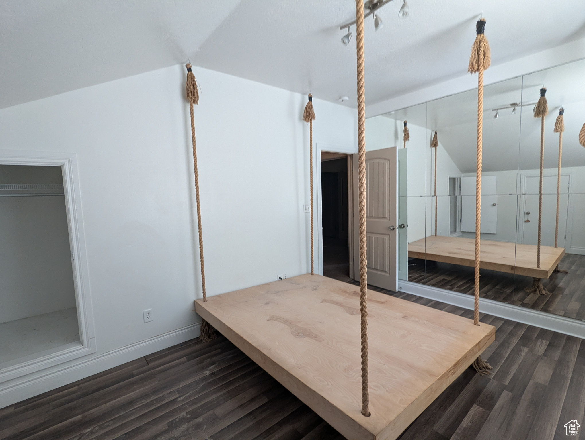 Unfurnished bedroom with dark wood-type flooring and lofted ceiling