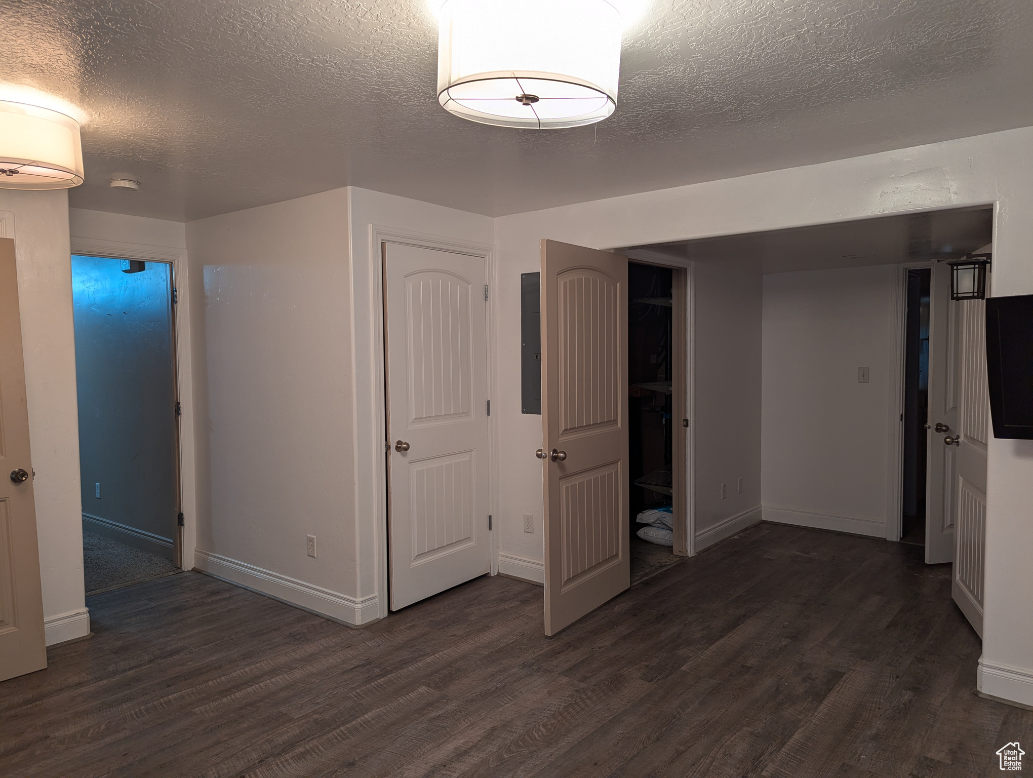 Unfurnished bedroom featuring a textured ceiling, electric panel, and dark hardwood / wood-style floors