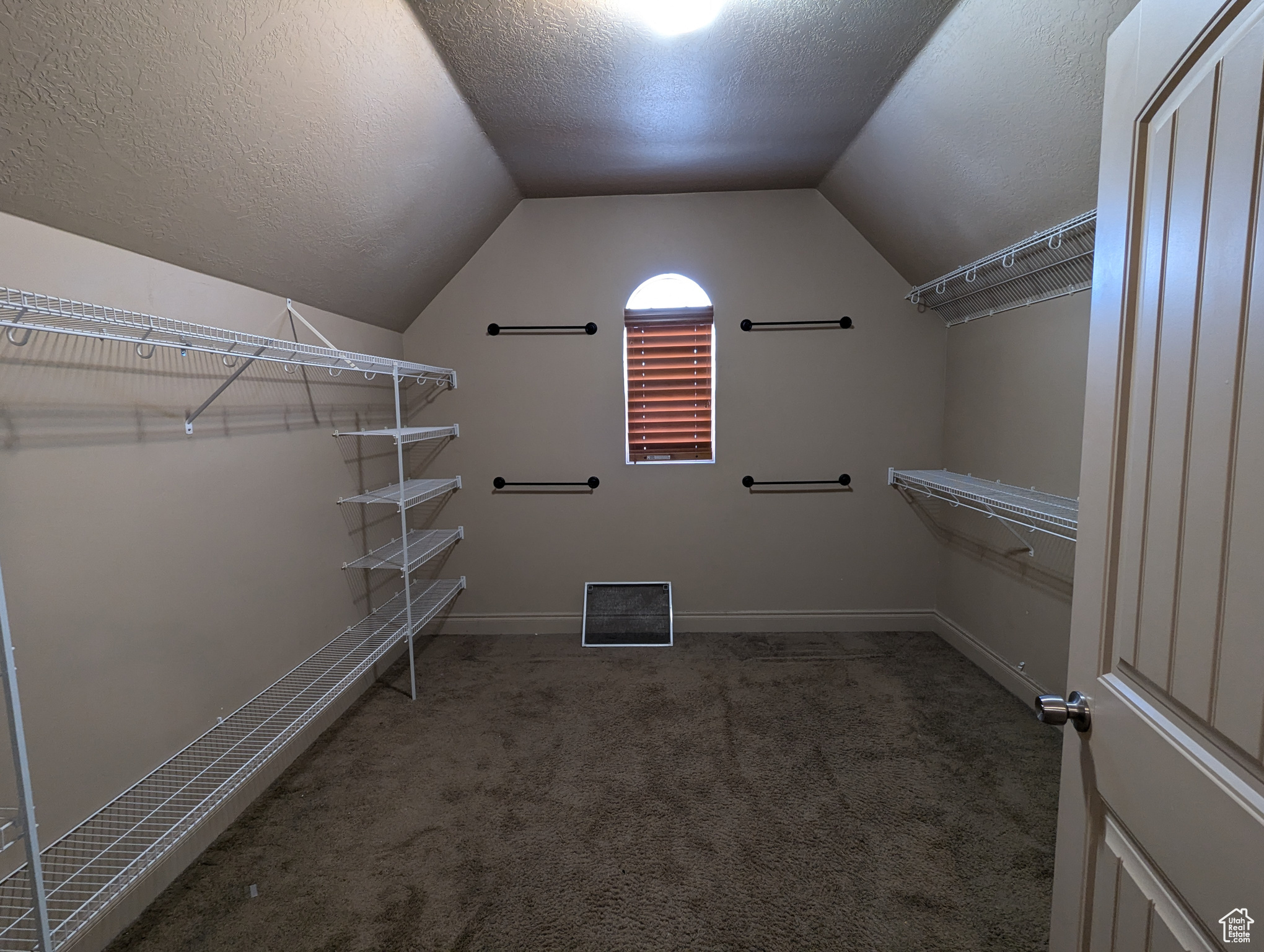 Walk in closet with lofted ceiling and dark colored carpet