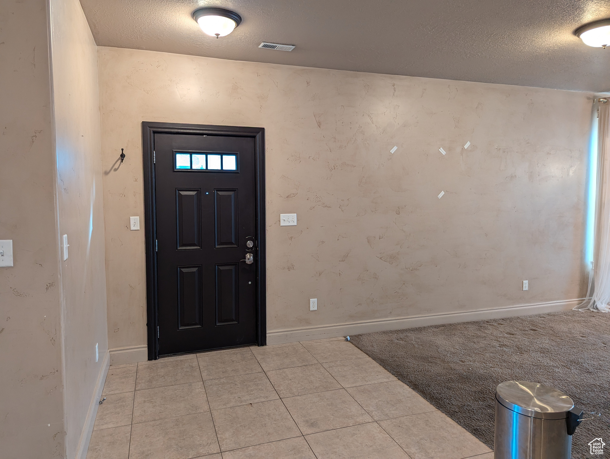 Foyer entrance with light tile patterned flooring and a textured ceiling