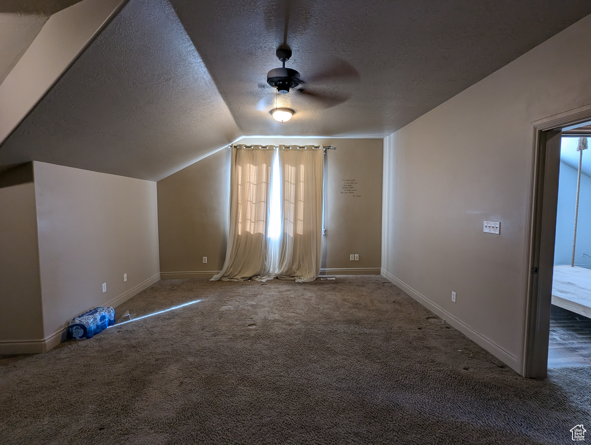 Additional living space featuring ceiling fan, dark colored carpet, a textured ceiling, and lofted ceiling