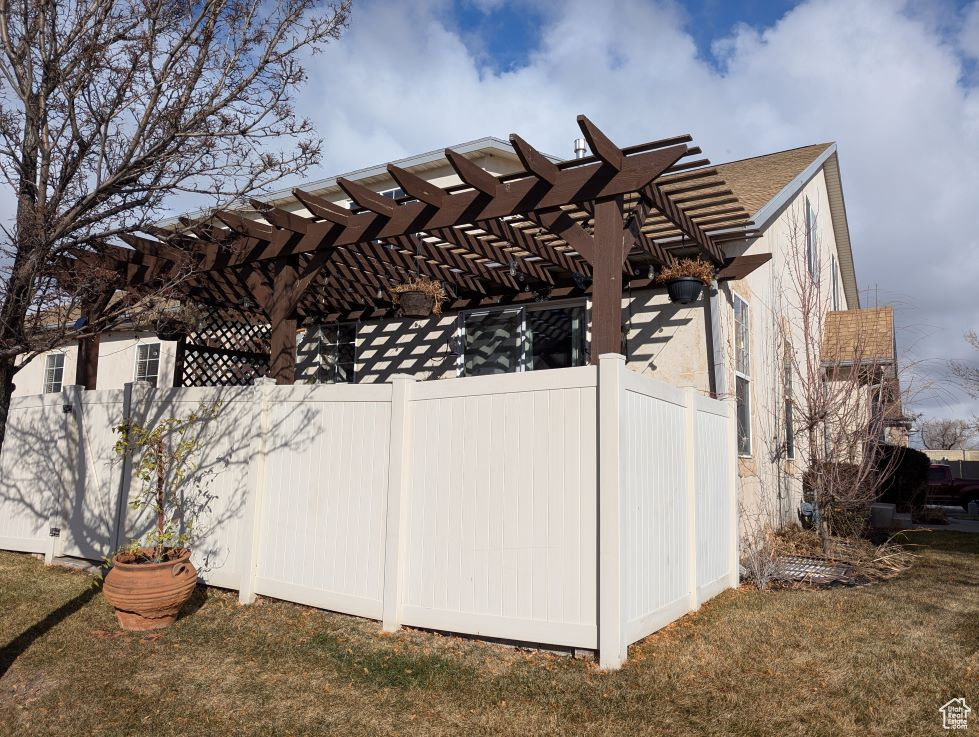 View of side of property with a pergola and a lawn