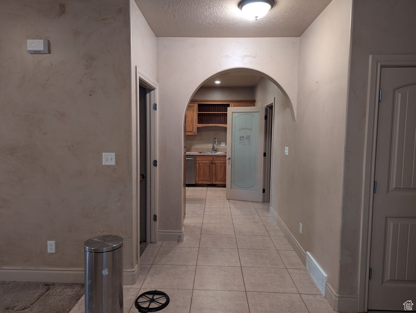 Hall with light tile patterned flooring, sink, and a textured ceiling