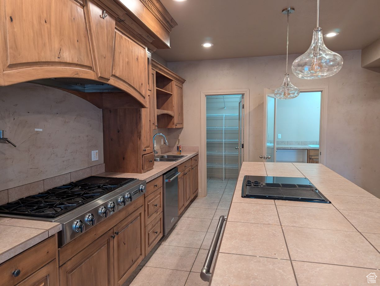 Kitchen with appliances with stainless steel finishes, decorative backsplash, sink, and tile counters