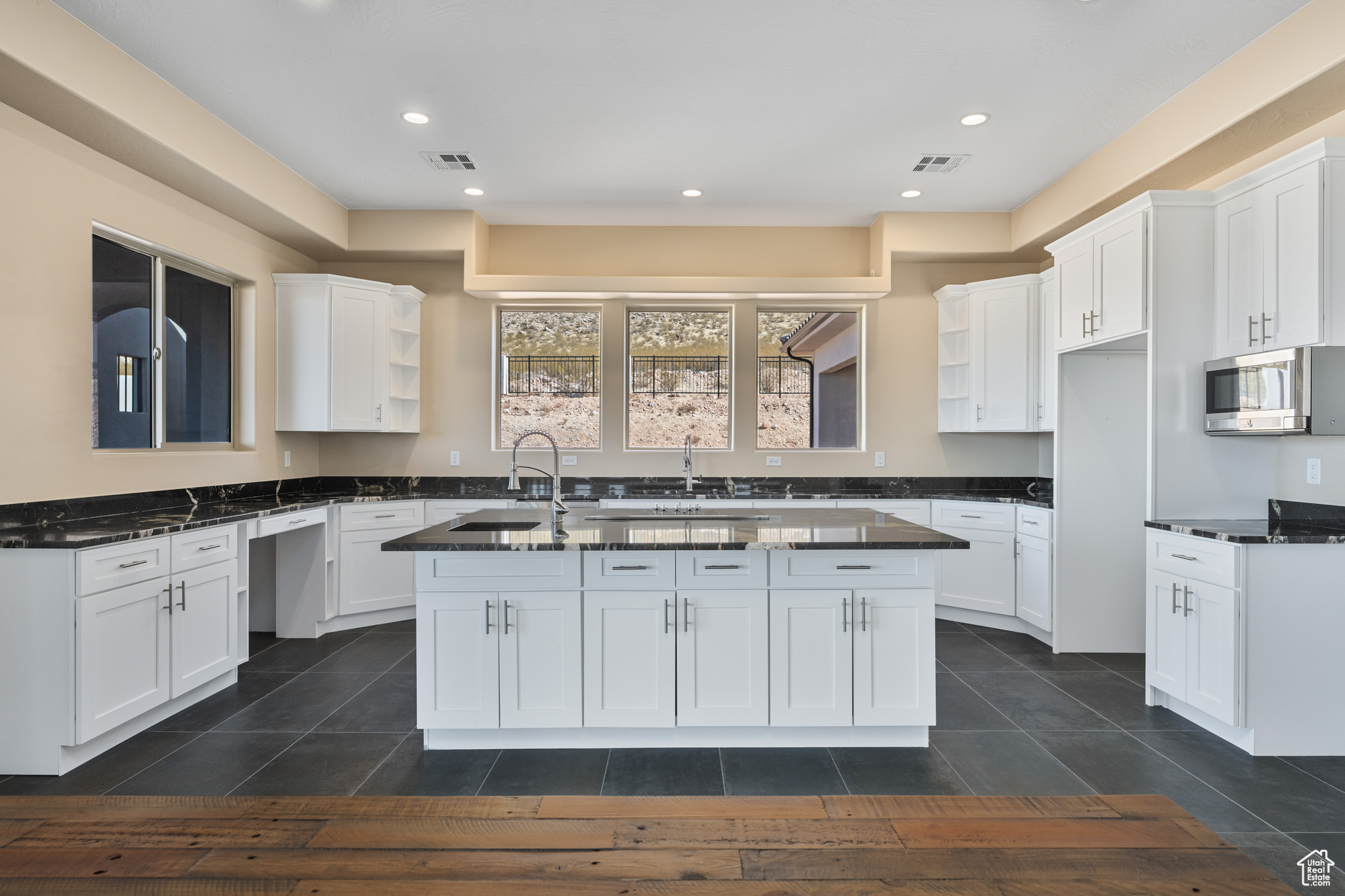 Kitchen with white cabinetry, sink, a kitchen island with sink, and dark tile patterned flooring