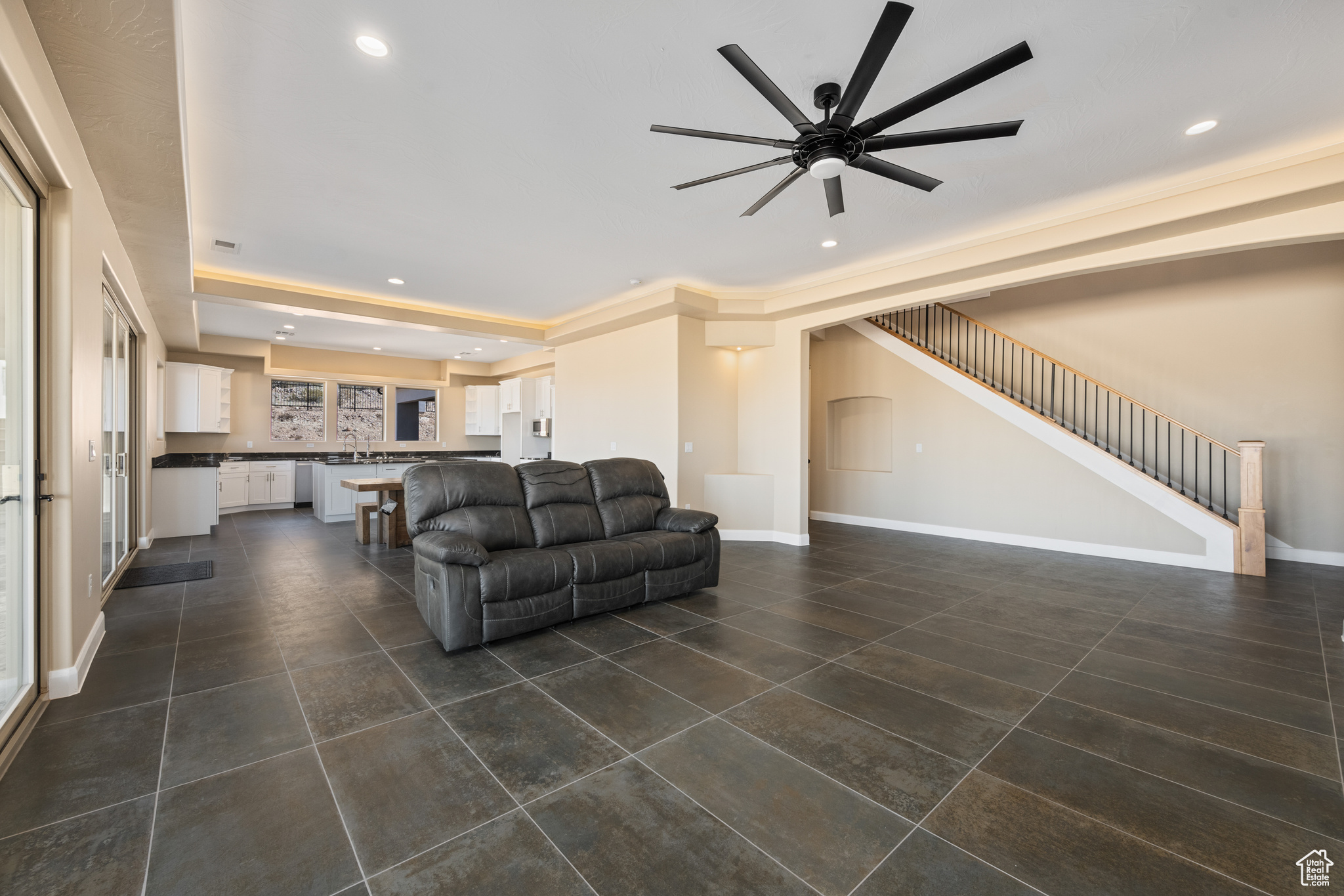Living room with ceiling fan and dark tile patterned floors