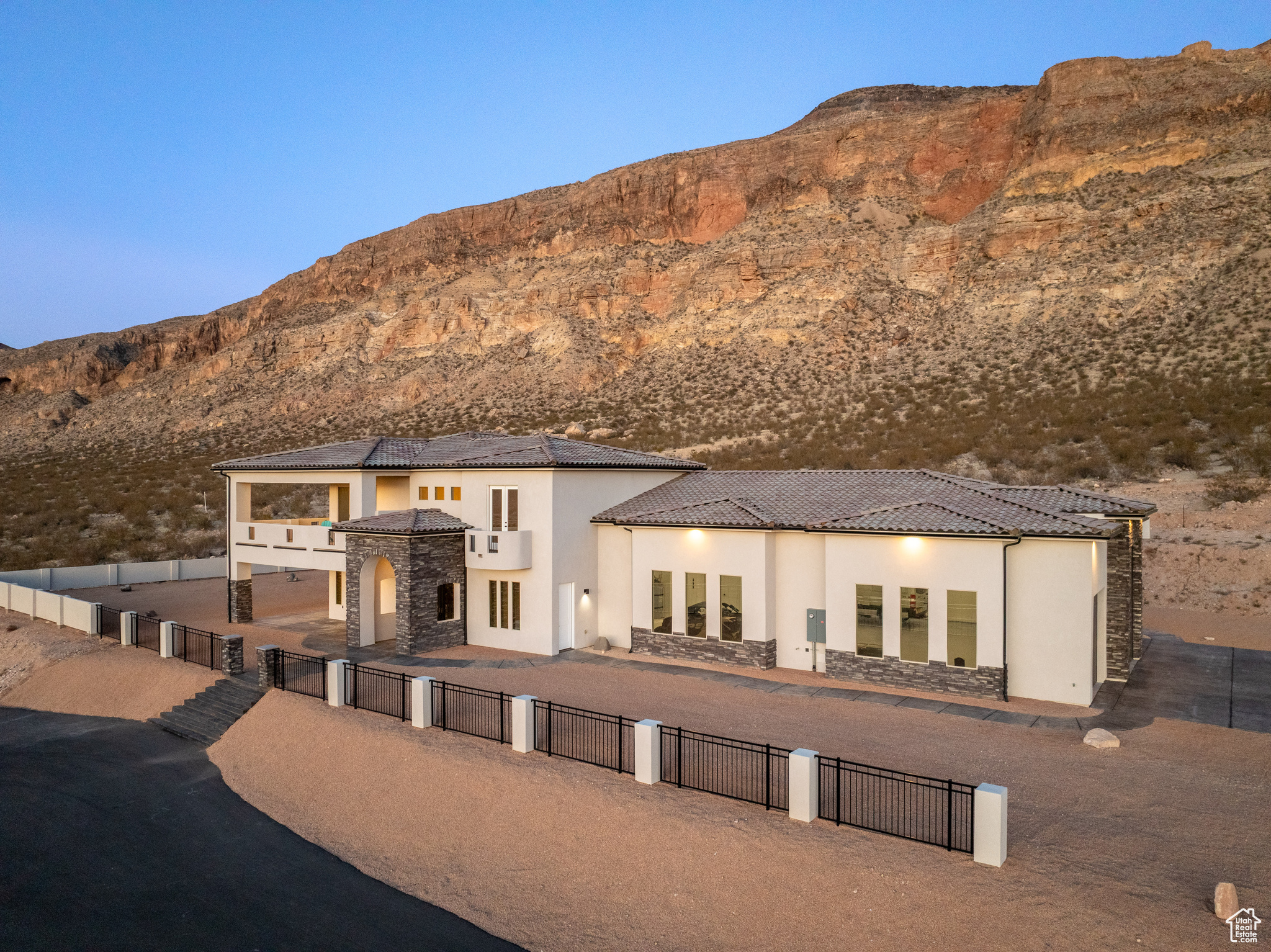 Back of house featuring fence private yard, stone siding, a mountain view, and stucco siding