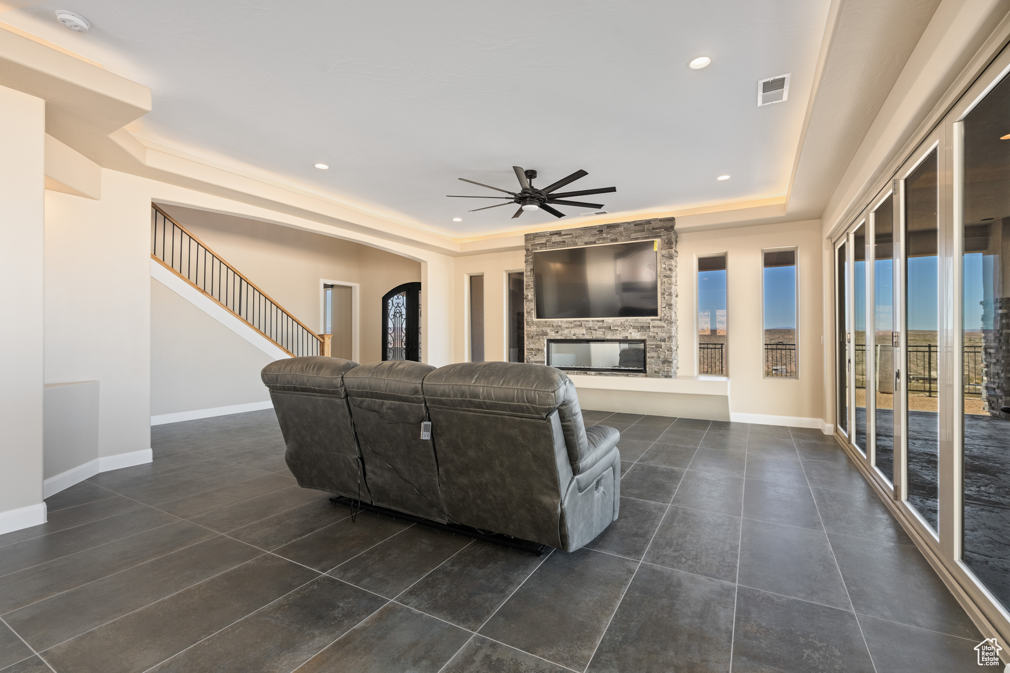 Living room with ceiling fan, a multi sided fireplace, and a raised ceiling