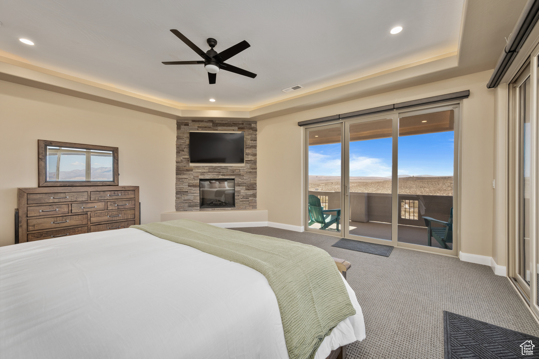 Carpeted bedroom with multiple windows, access to outside, and a tray ceiling