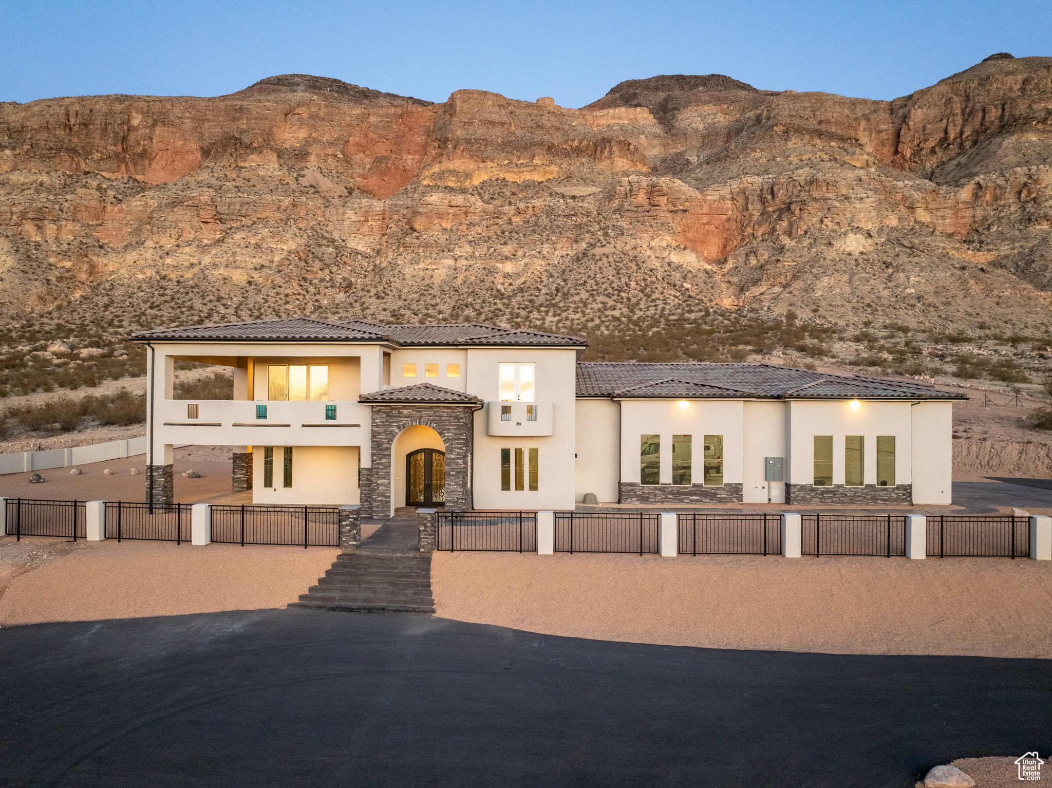 View of front facade with a fenced front yard, stone siding, a mountain view, and stucco siding