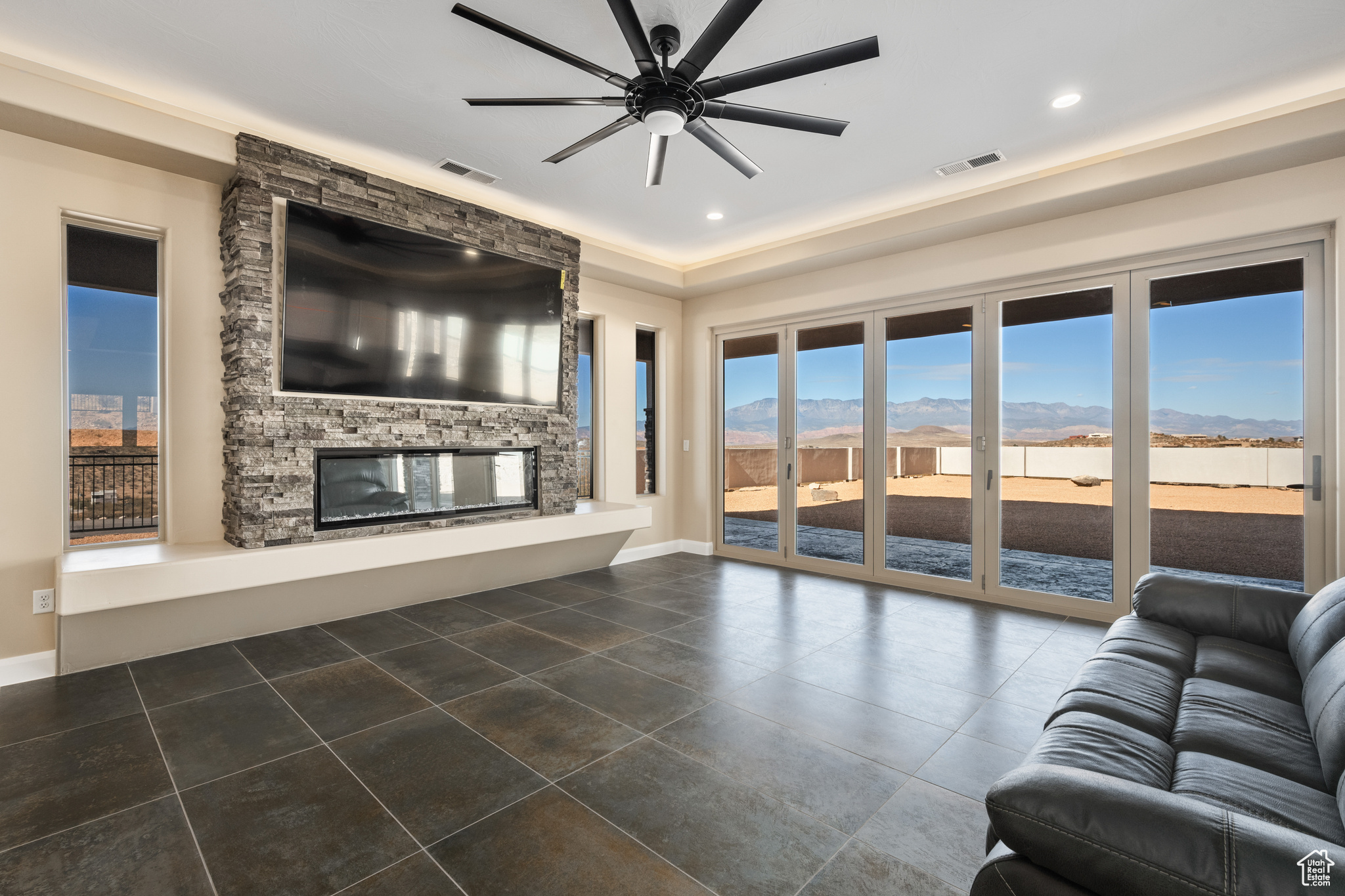 Unfurnished living room with a stone fireplace and ceiling fan