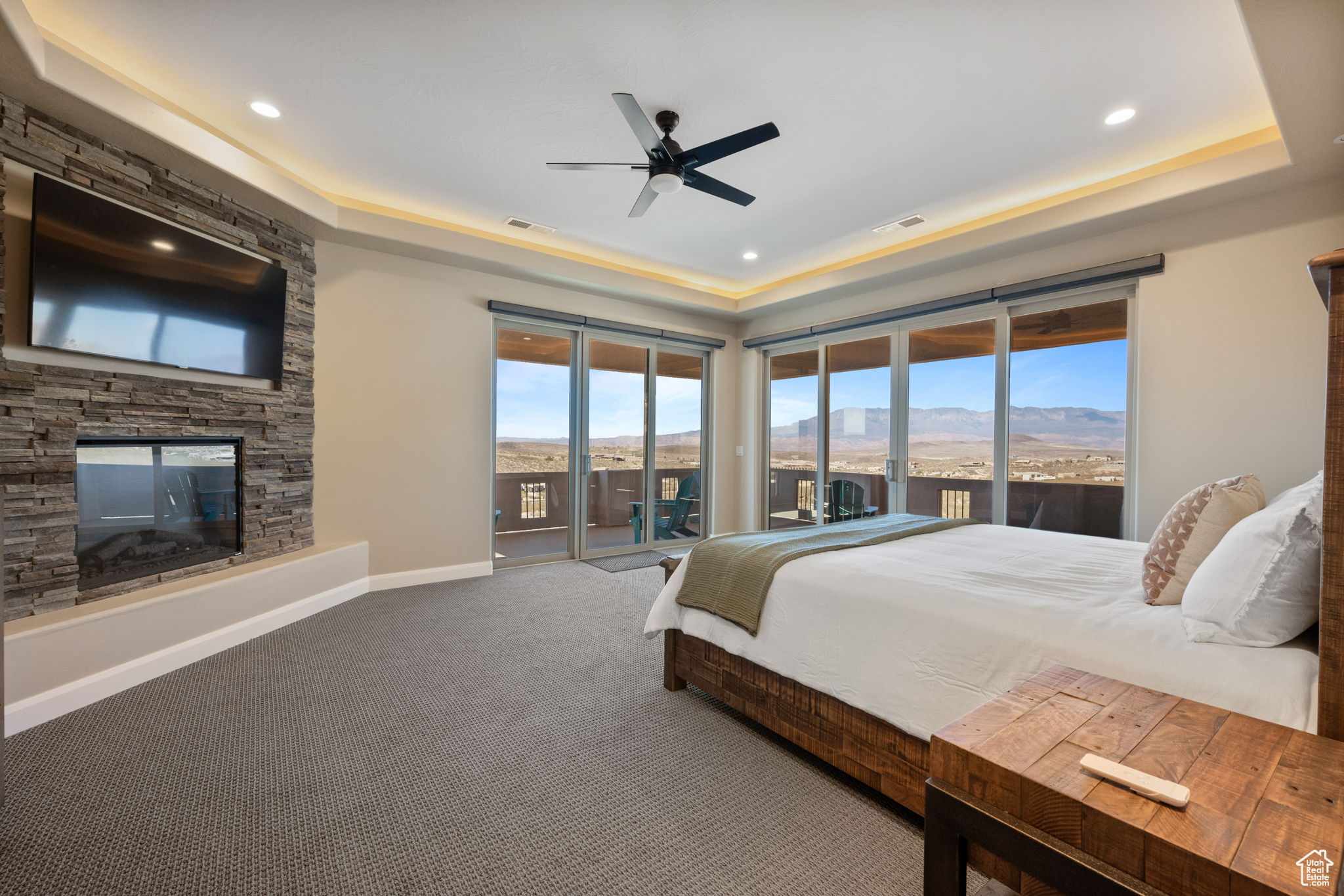 Bedroom featuring multiple windows, access to exterior, a fireplace, a mountain view, and a raised ceiling