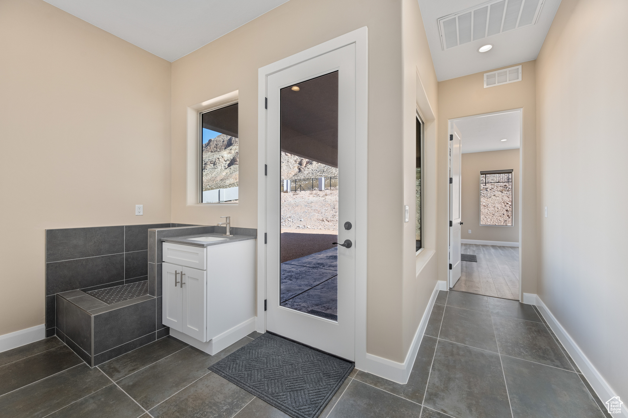 Doorway to outside with sink, a wealth of natural light, and dark tile patterned flooring