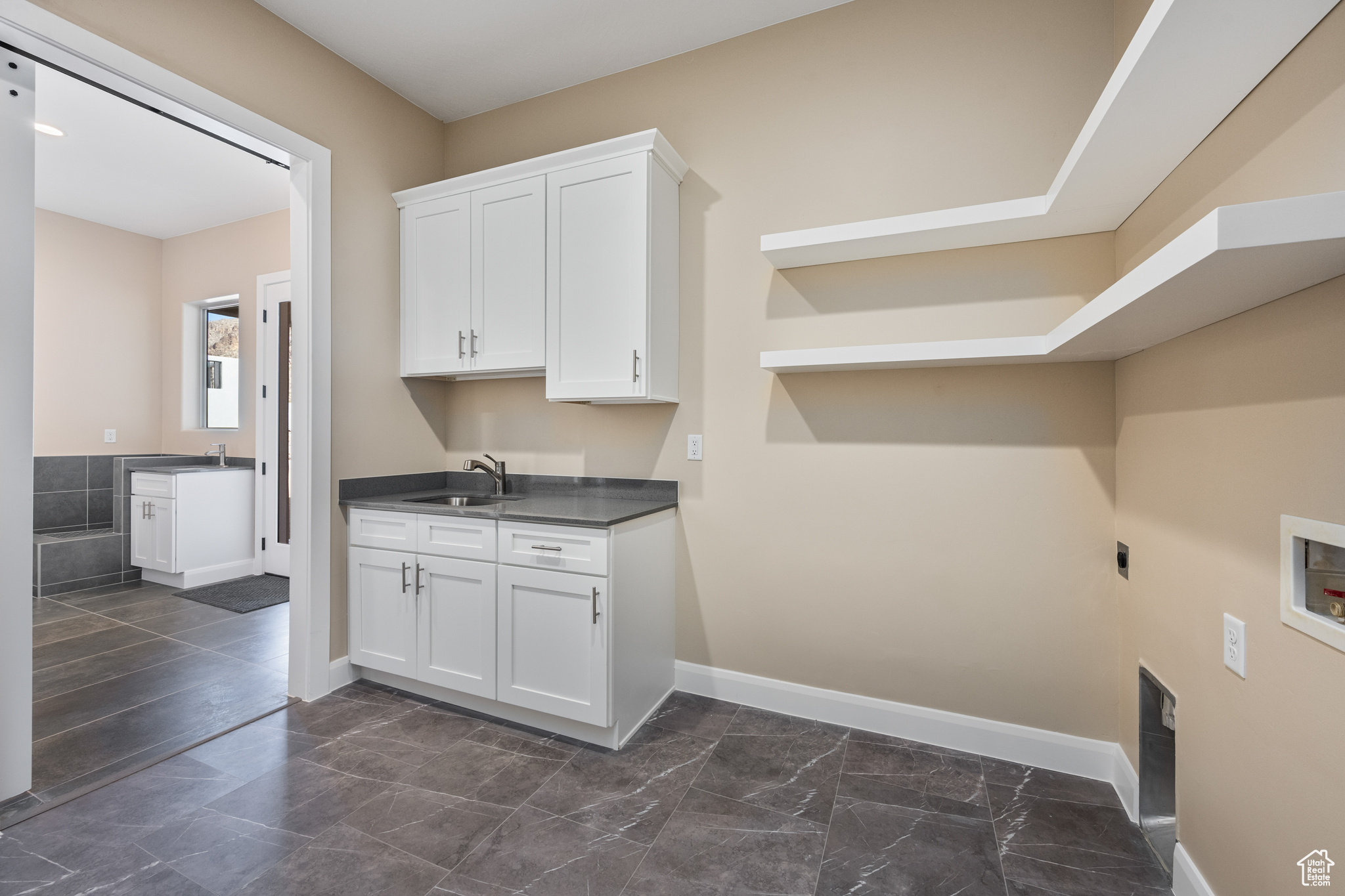 Laundry area featuring electric dryer hookup, sink, hookup for a washing machine, and cabinets