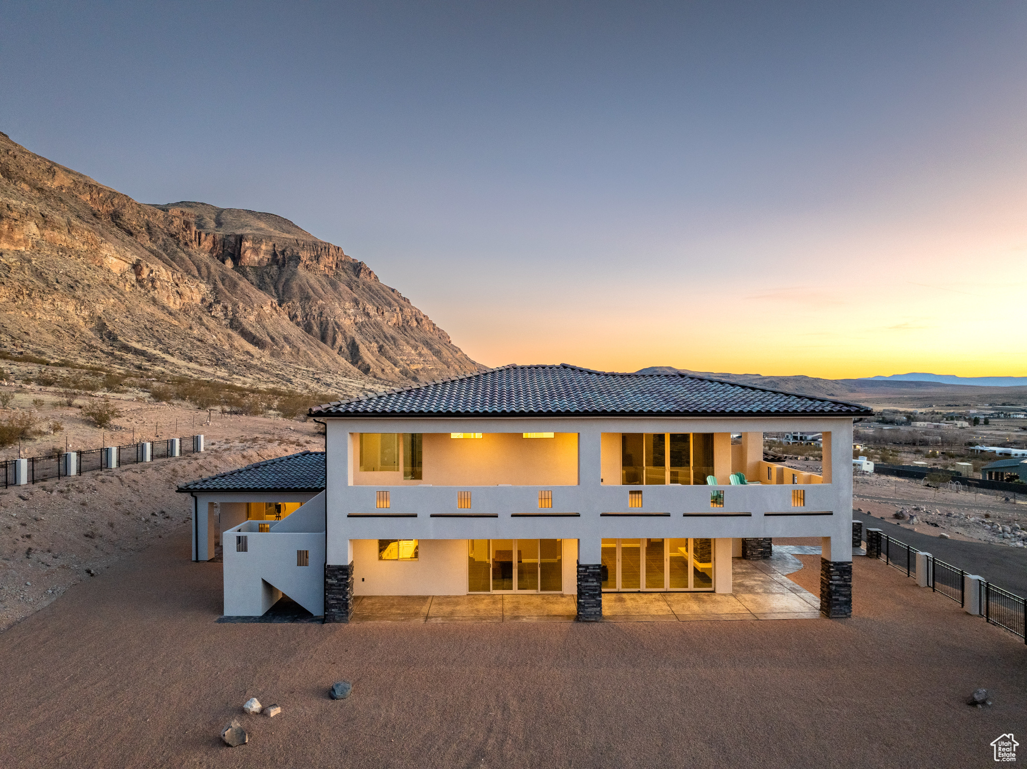 Back of property at dusk with a tile roof, a mountain view, and stucco siding