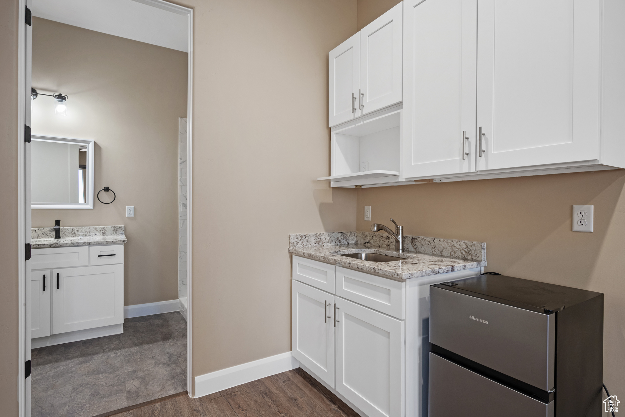 Interior space with white cabinetry, light stone countertops, sink, and dark hardwood / wood-style flooring