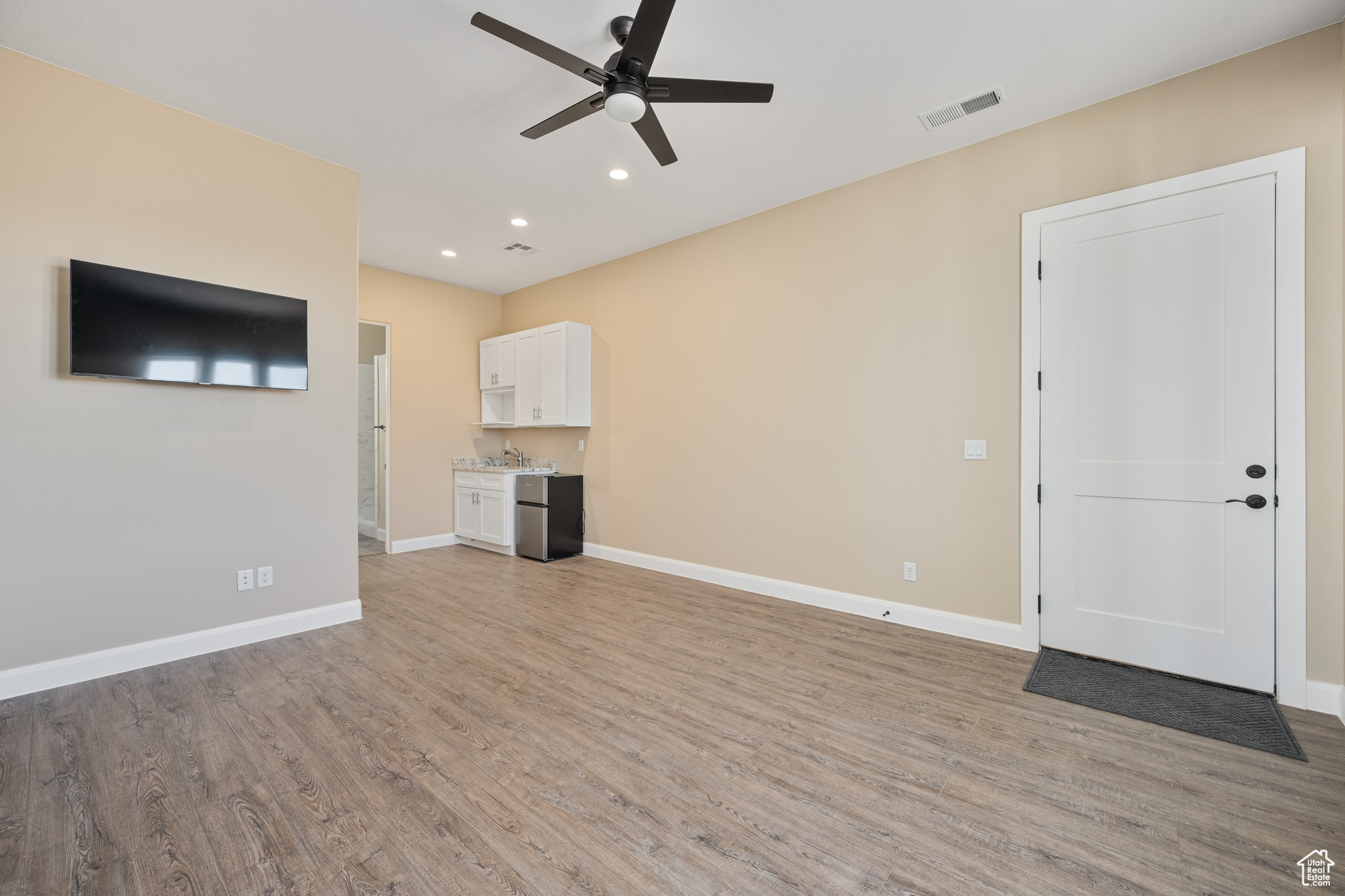 Unfurnished living room with ceiling fan, sink, and light hardwood / wood-style floors