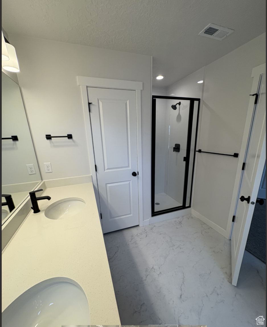 Bathroom featuring vanity, an enclosed shower, and a textured ceiling