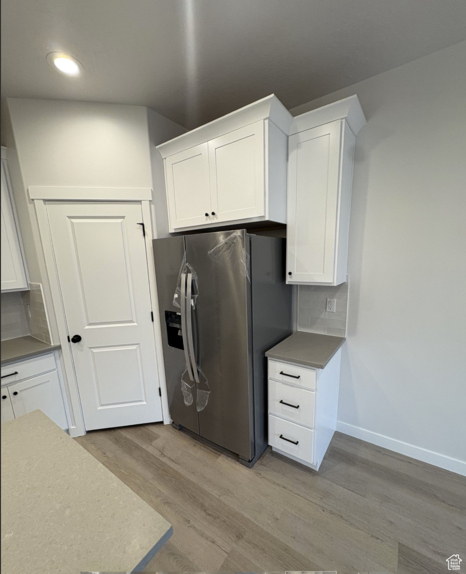 Kitchen with white cabinetry and stainless steel refrigerator with ice dispenser