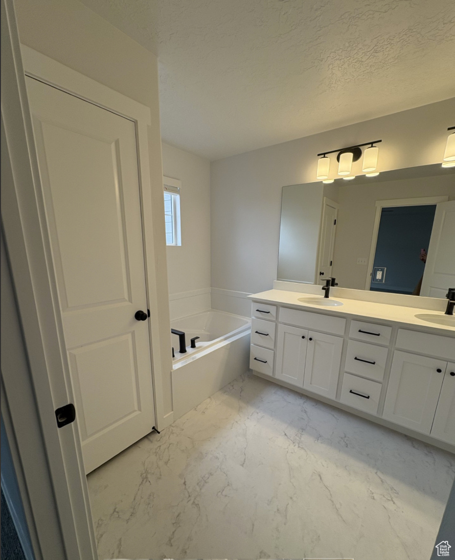 Bathroom with vanity, a bathtub, and a textured ceiling
