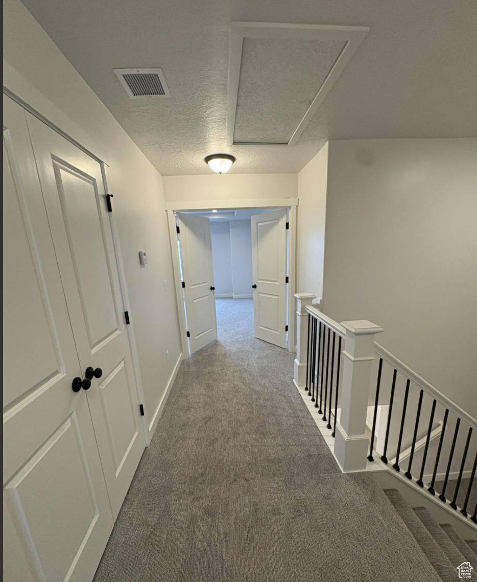 Corridor featuring carpet floors and a textured ceiling