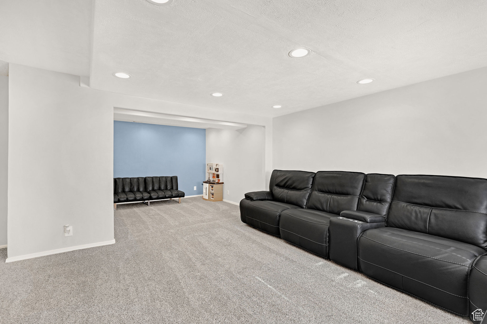 Basement family room with extra space to the back with the accented wall
