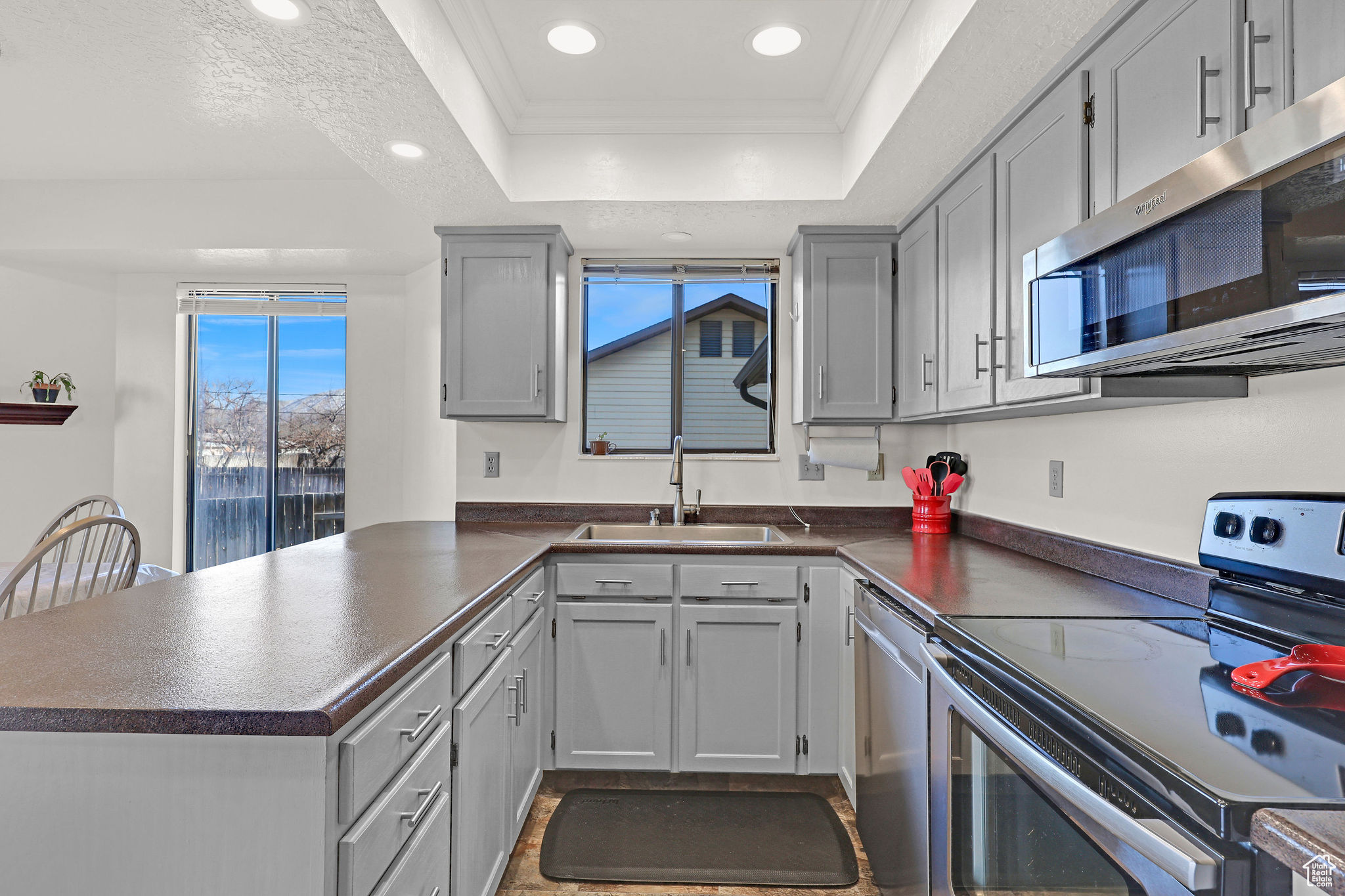 Kitchen with gray cabinets, sink, stainless steel appliances and glass top range