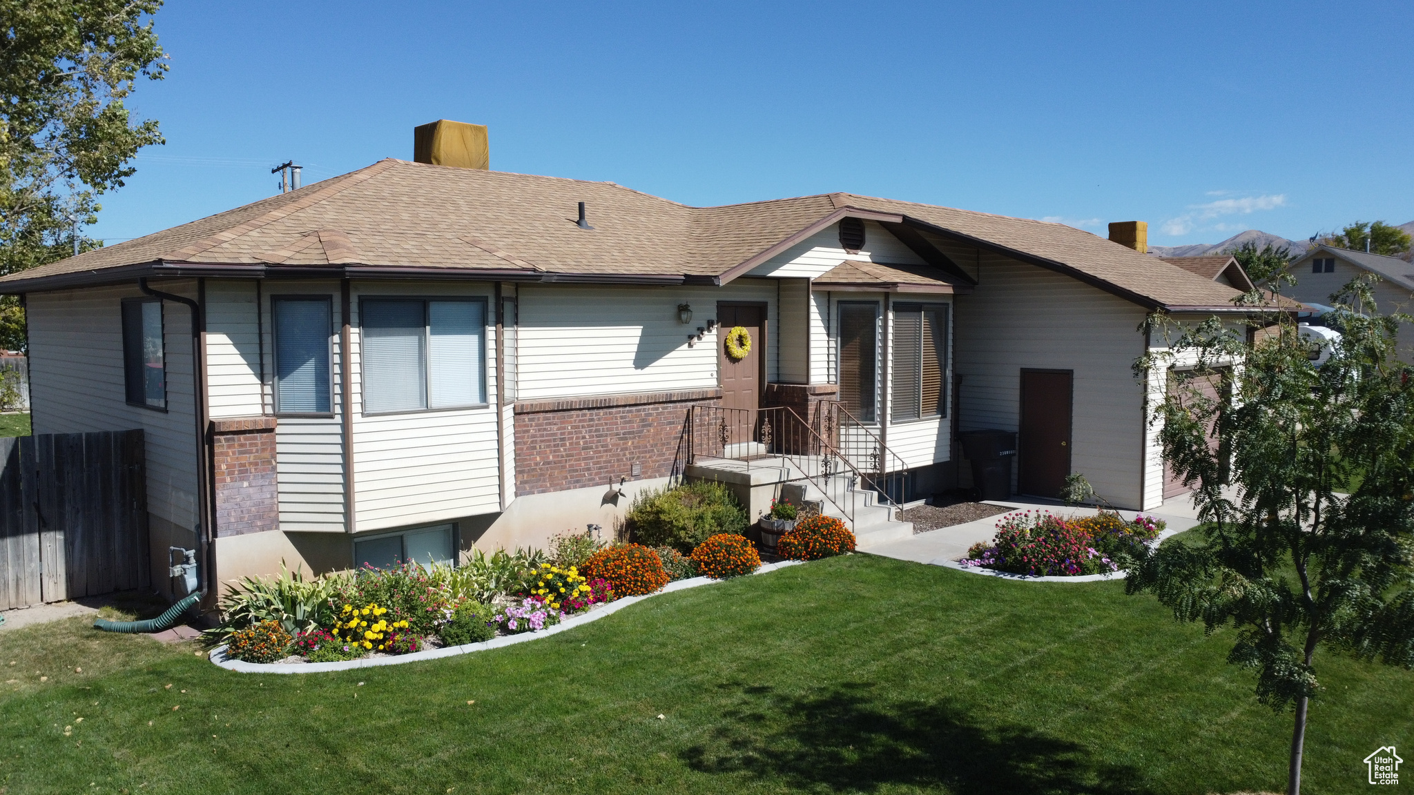 View of front facade featuring brick and siding. Front yard with flowers.