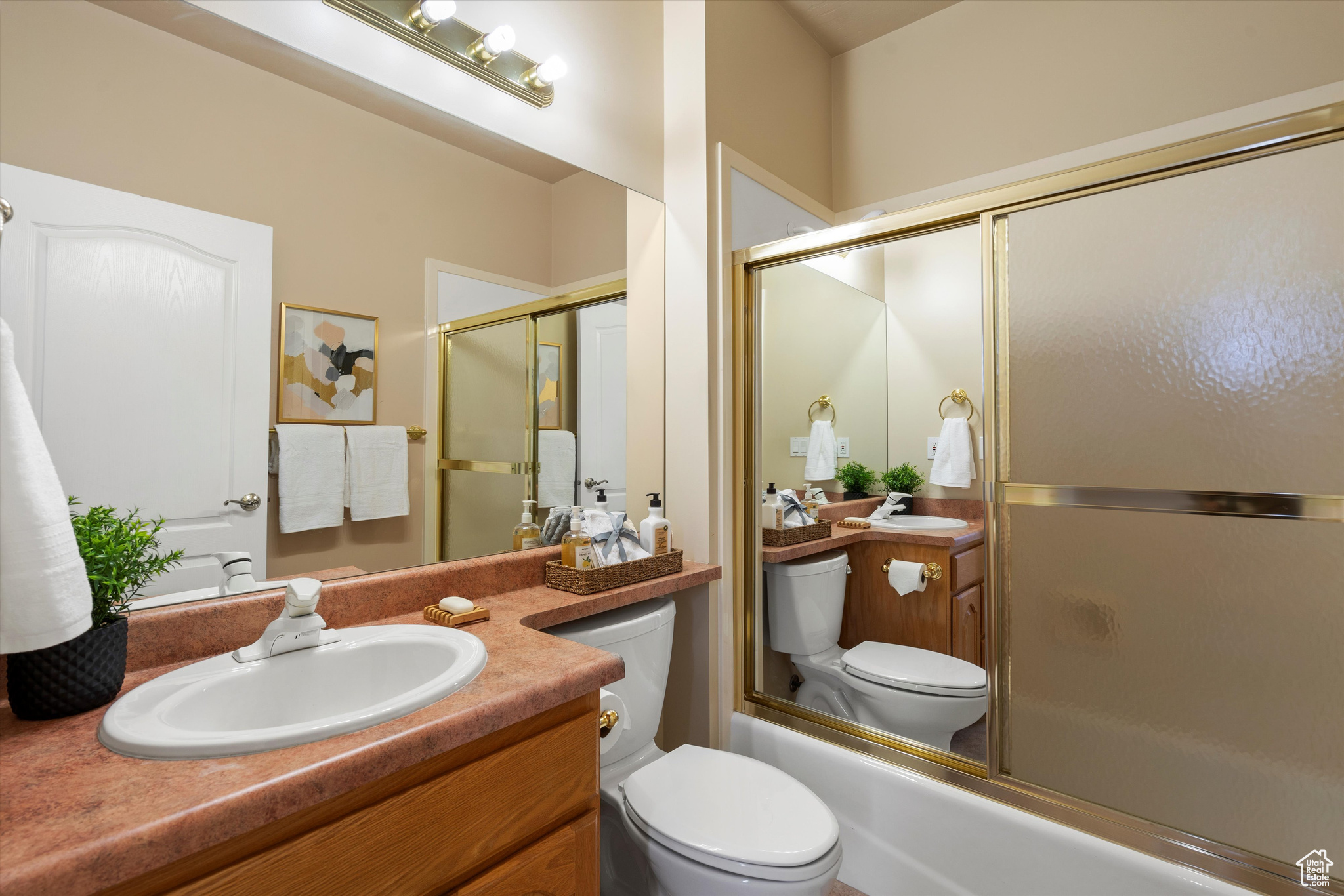 Full bathroom featuring toilet, vanity, and combined bath / shower with glass door