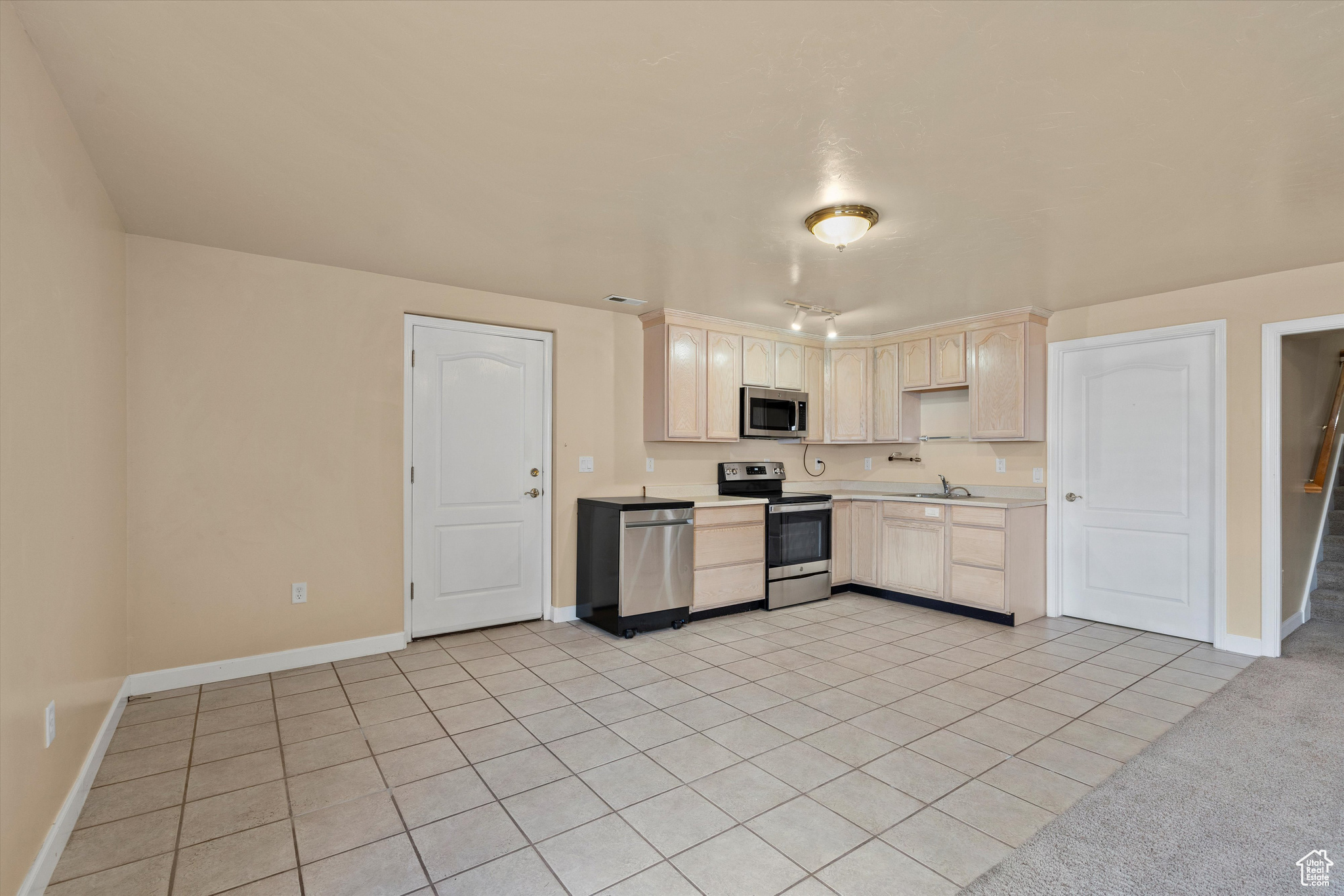 Kitchen featuring light tile patterned floors, sink, and stainless steel appliances