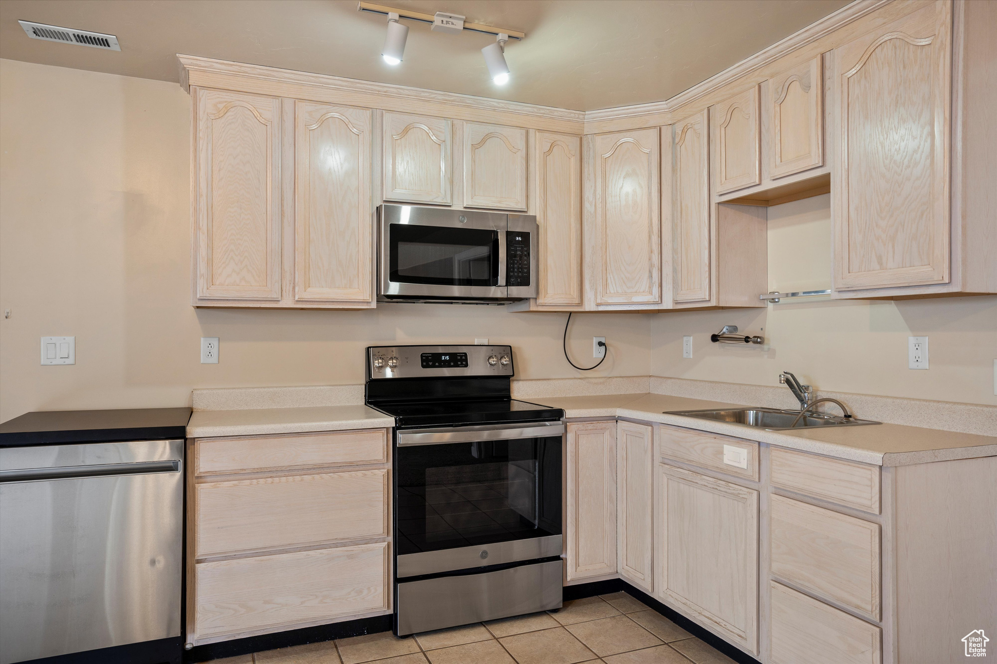 Kitchen with sink, light brown cabinets, and stainless steel appliances