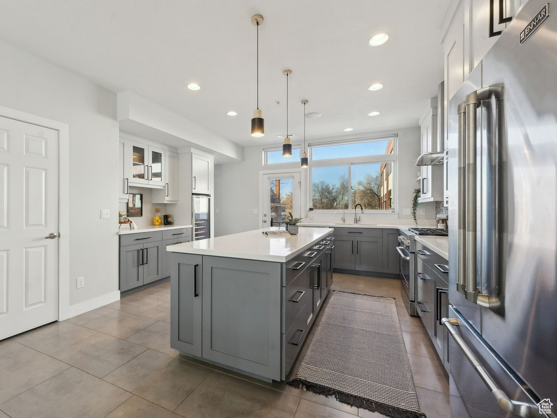 Kitchen with white cabinetry, high quality appliances, gray cabinets, and a center island