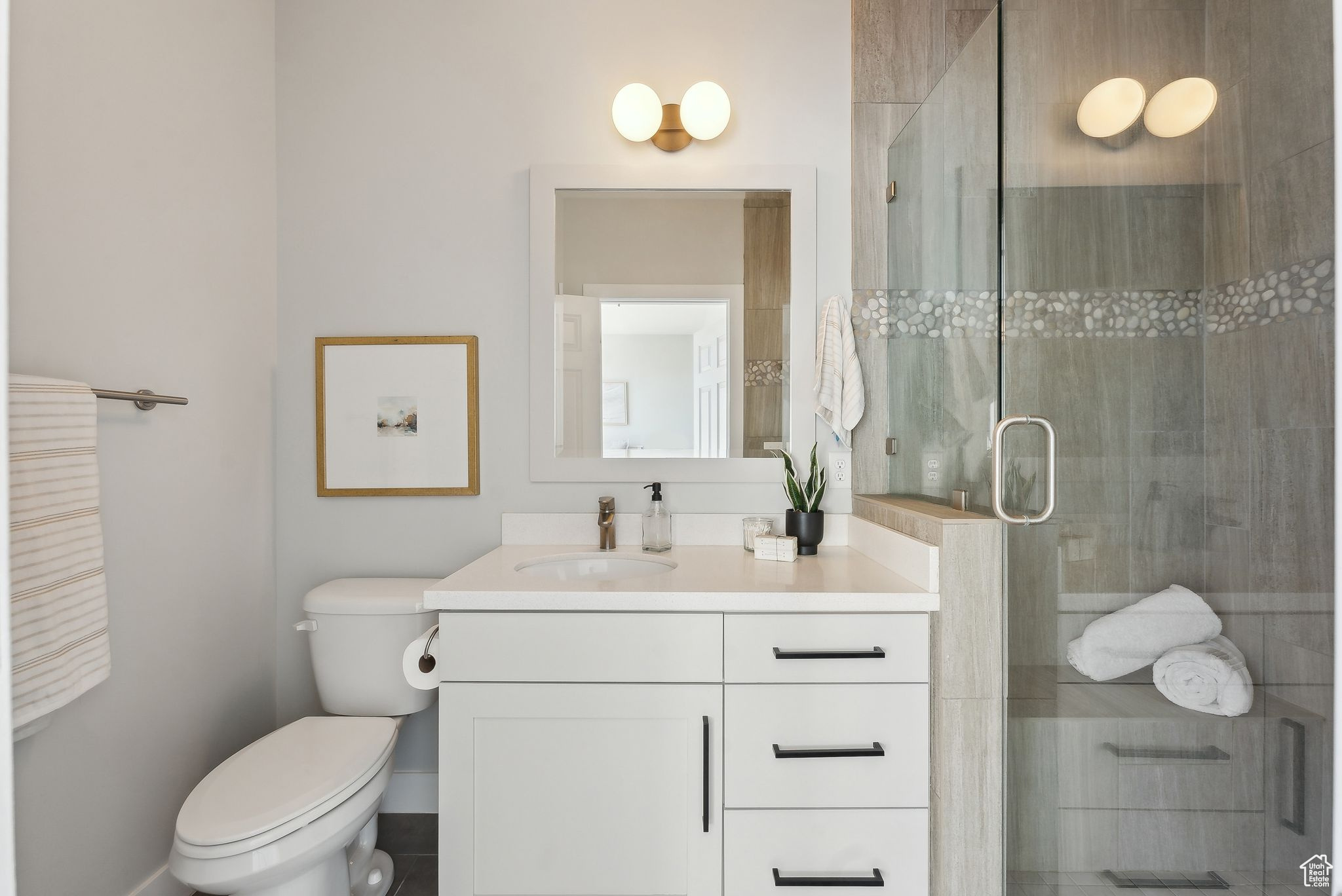 Ensuite bathroom with vanity, a shower with shower door, and toilet