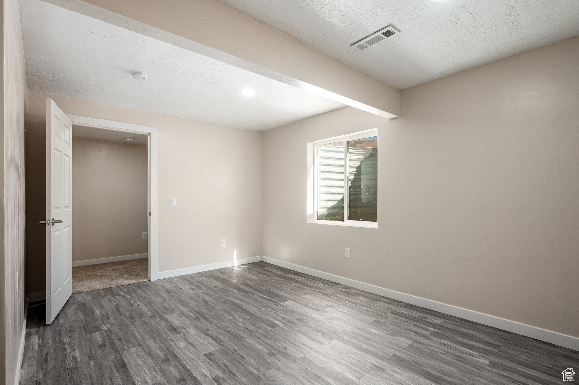 Unfurnished room with a textured ceiling and dark hardwood / wood-style floors