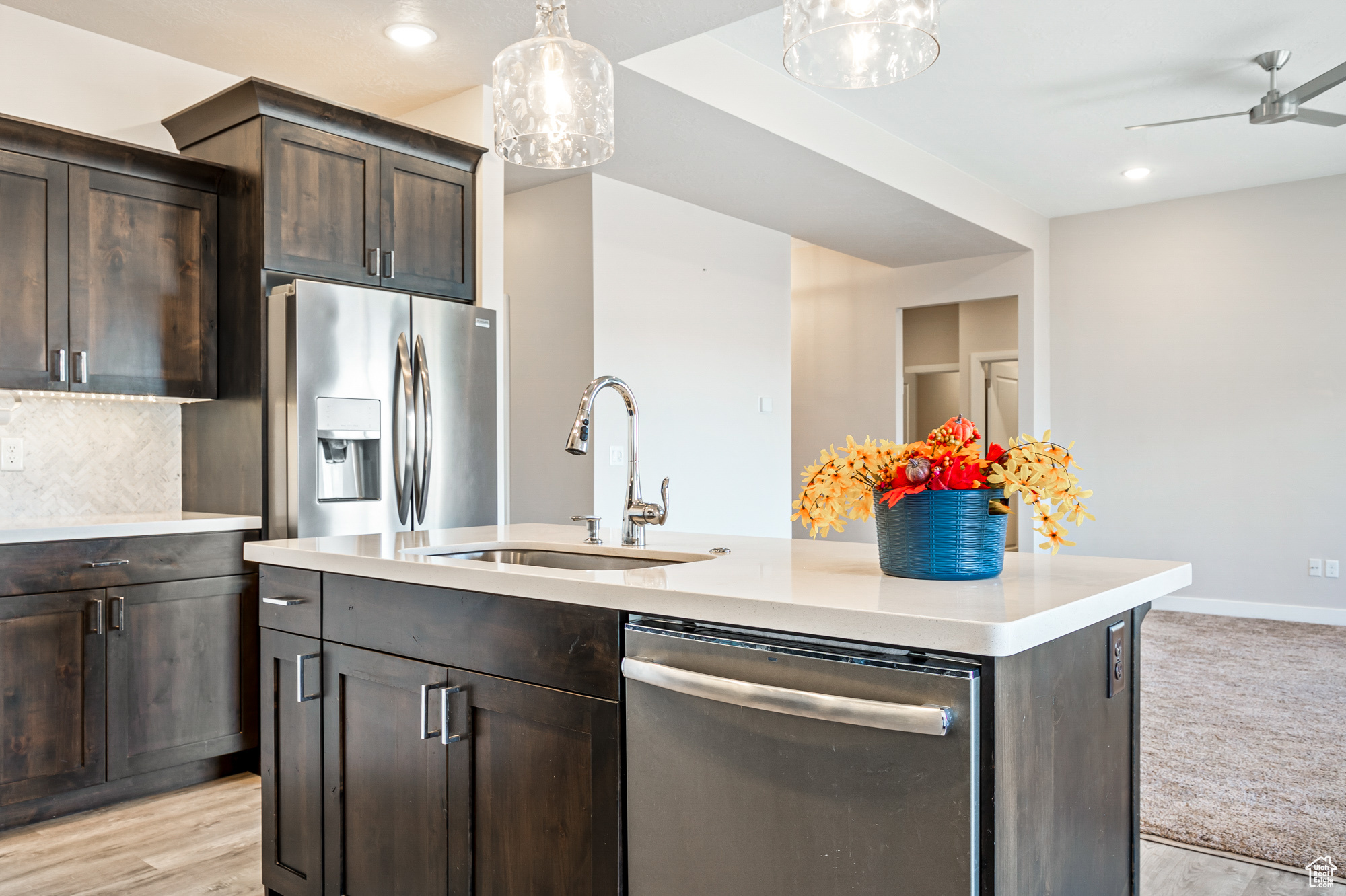 Kitchen featuring dark brown cabinets, sink, stainless steel appliances, and an island with sink