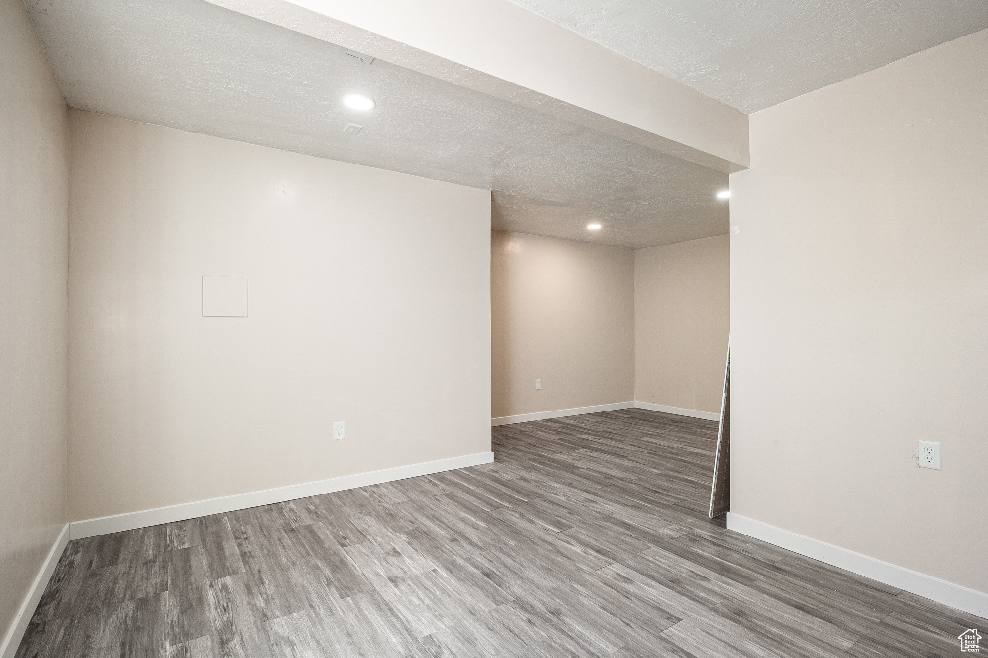 Basement with a textured ceiling and hardwood / wood-style flooring