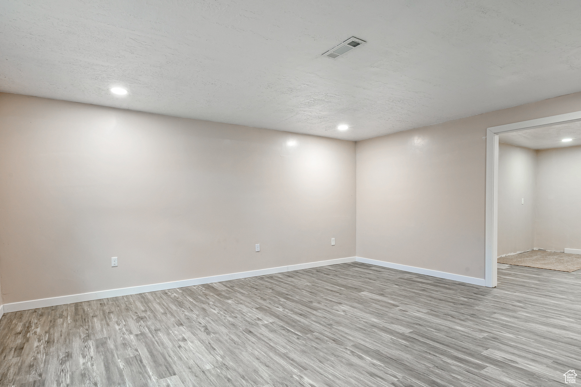 Basement with light hardwood / wood-style floors and a textured ceiling