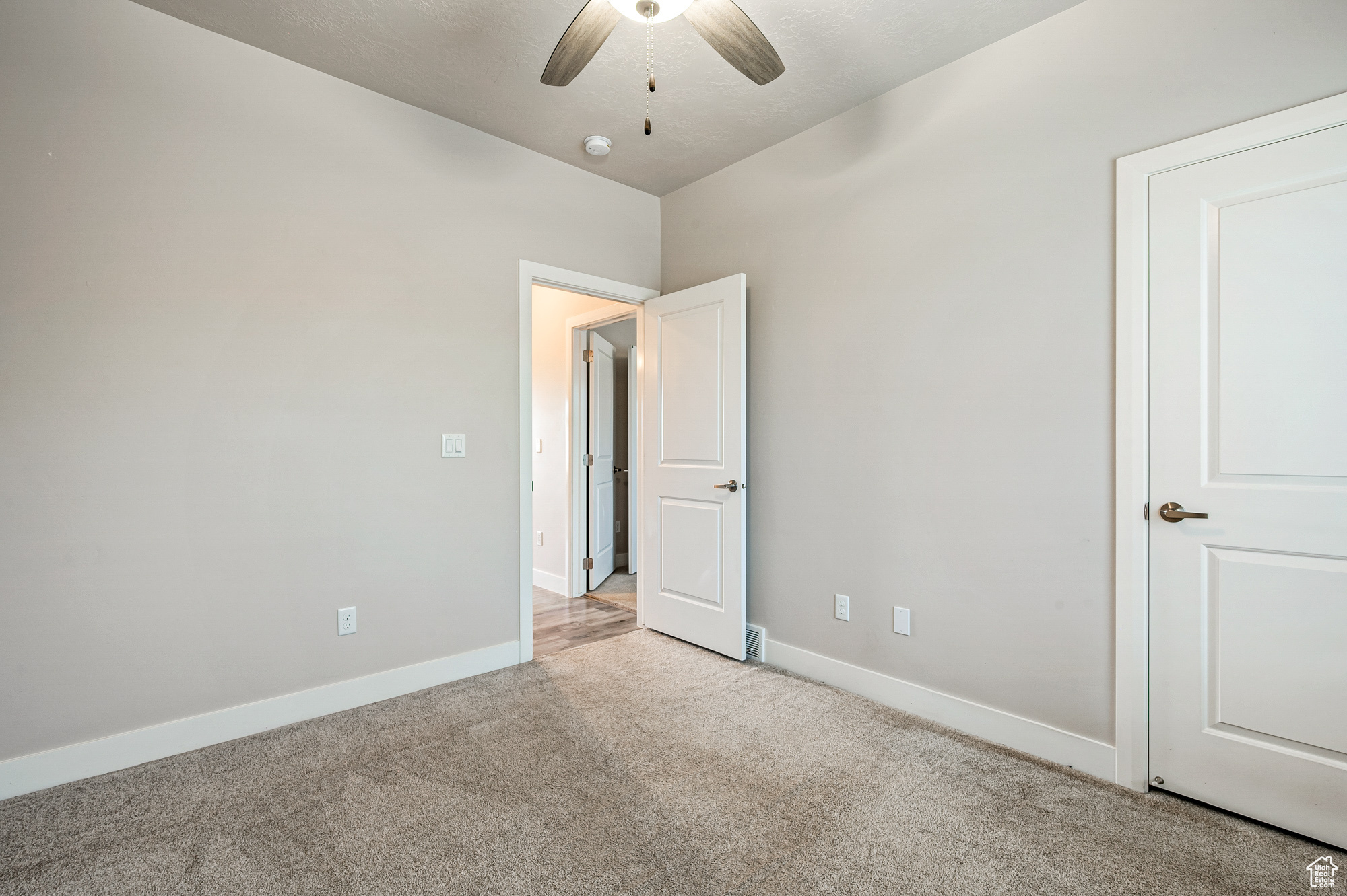 Unfurnished bedroom featuring ceiling fan and light carpet