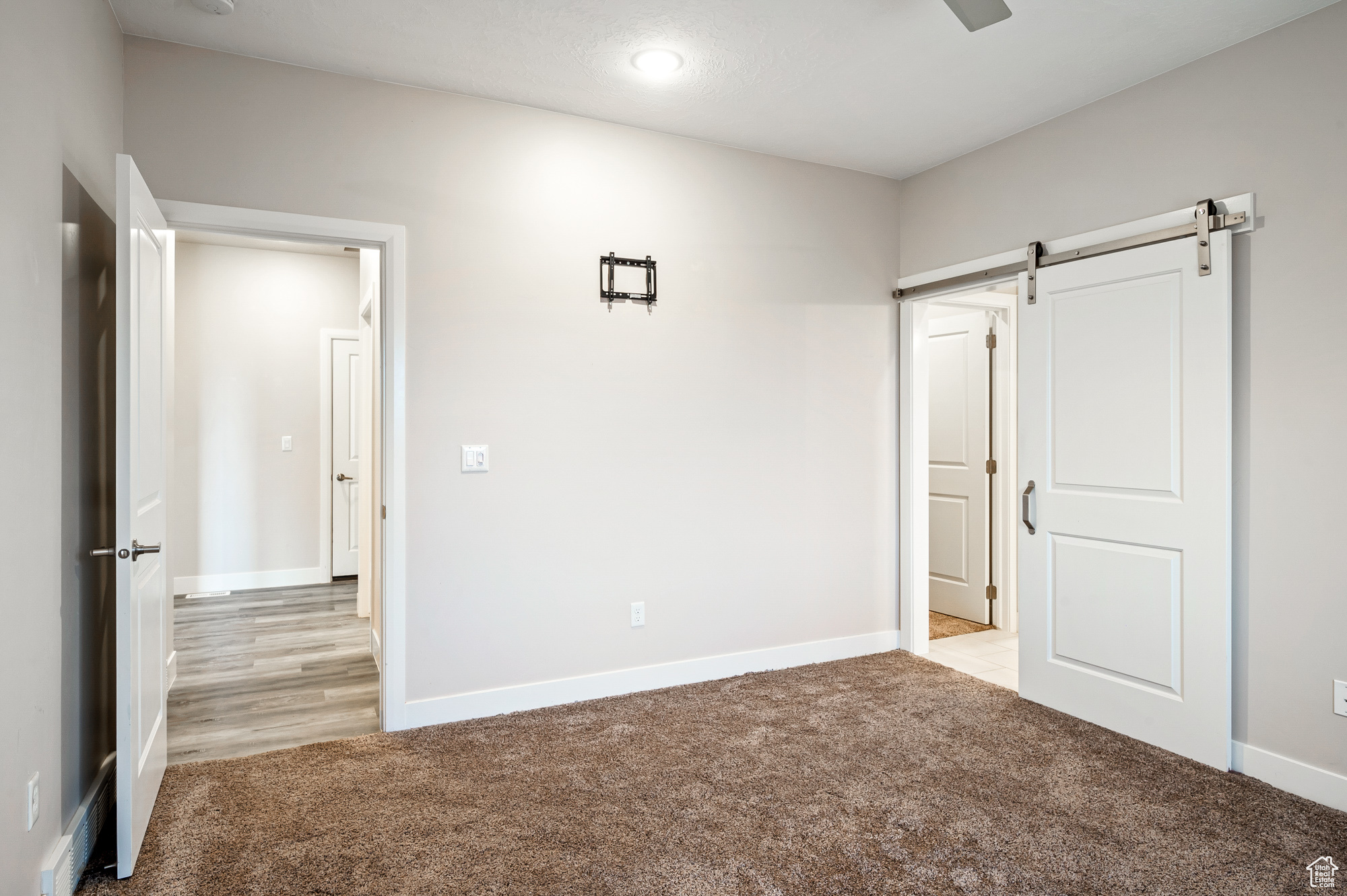 Unfurnished bedroom featuring light colored carpet and a barn door