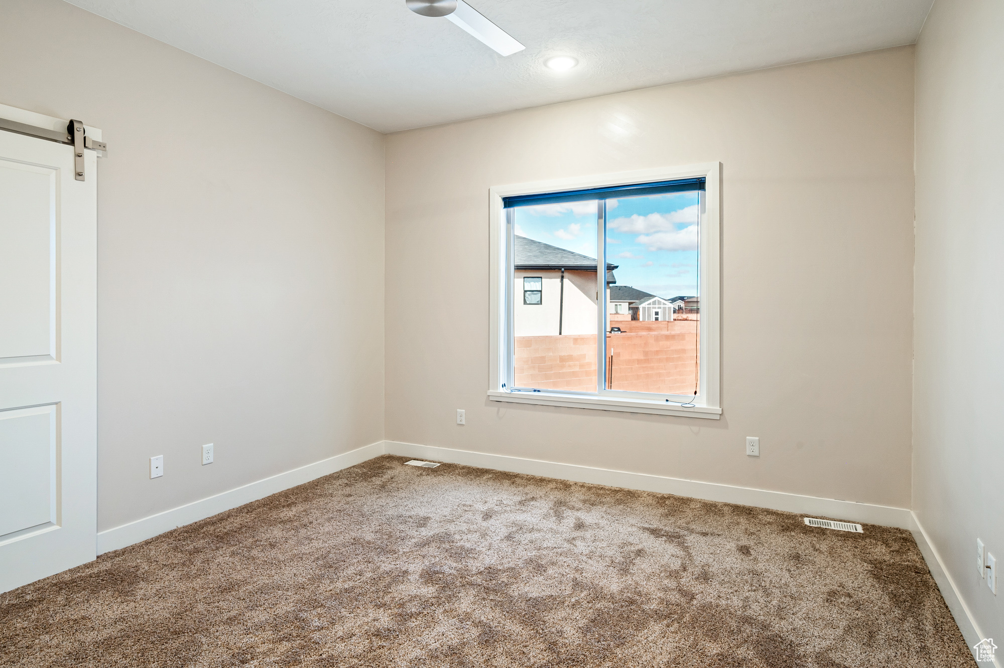 Unfurnished room featuring a barn door and carpet floors