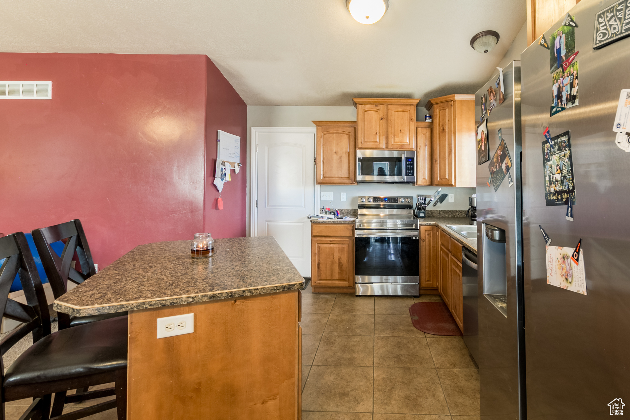 Kitchen featuring a center island, appliances with stainless steel finishes, a kitchen breakfast bar, and dark tile patterned floors