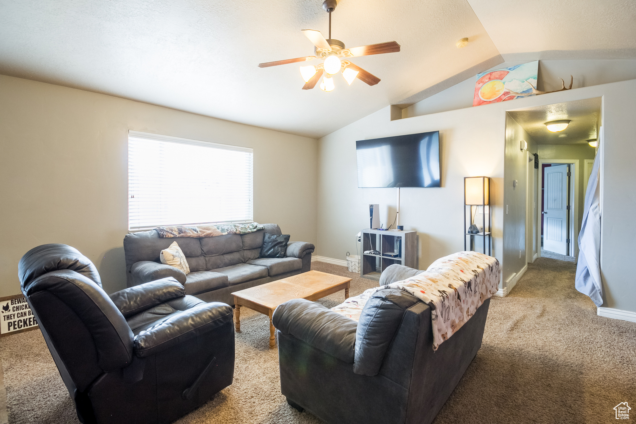 Carpeted living room with lofted ceiling and ceiling fan