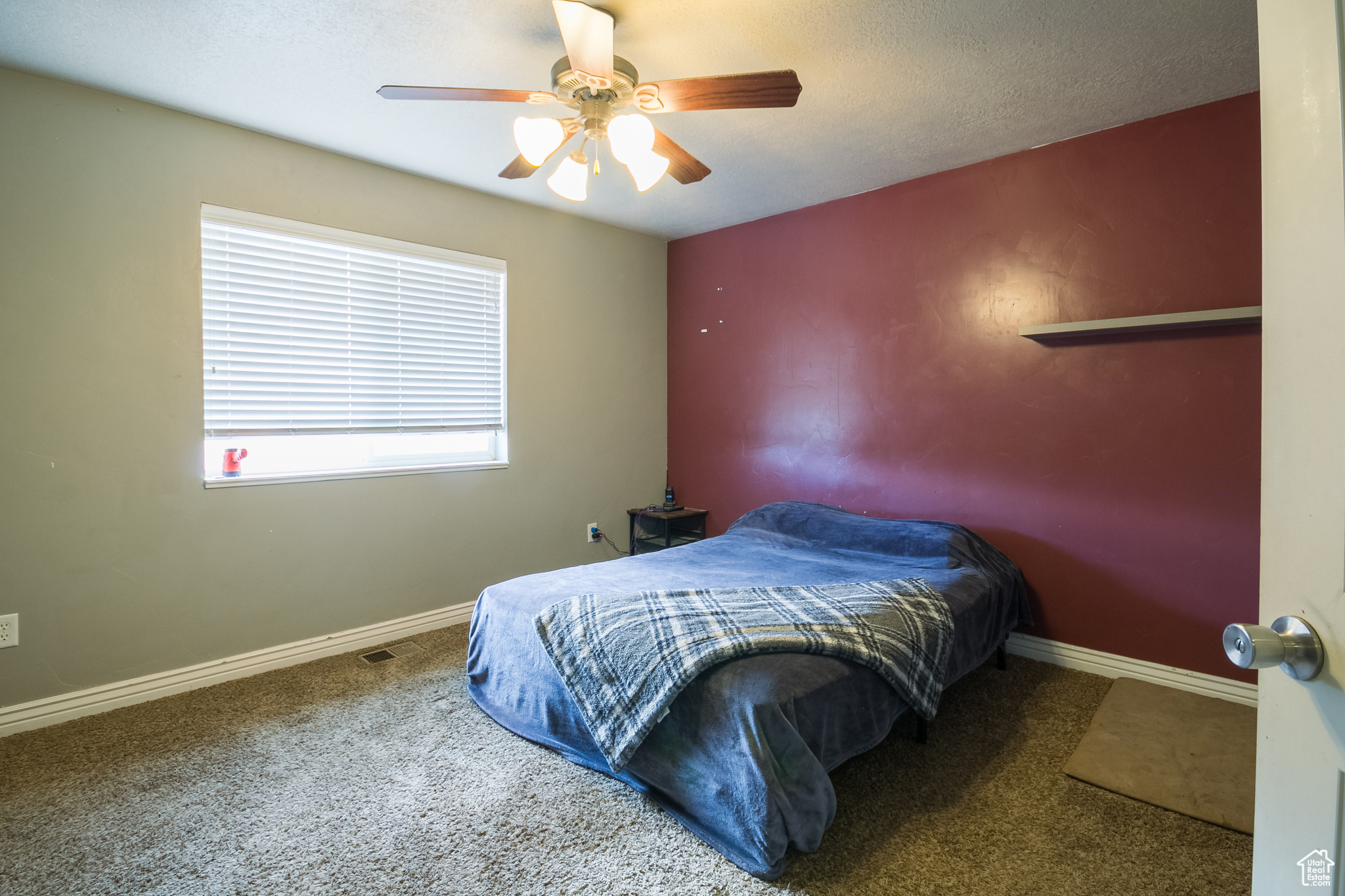 Carpeted bedroom featuring ceiling fan and a textured ceiling
