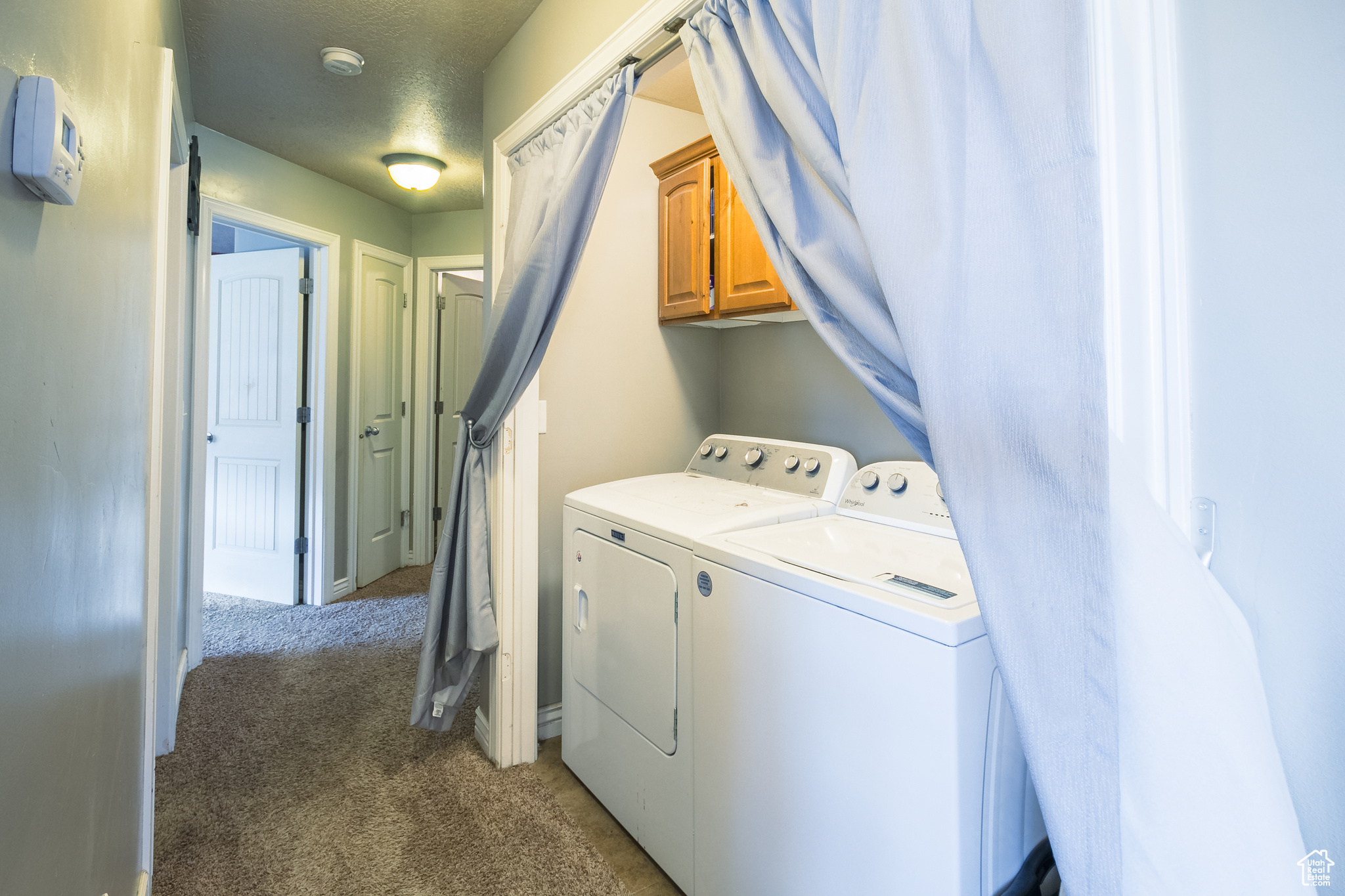 Laundry area featuring washer and dryer, cabinets, a textured ceiling, and carpet